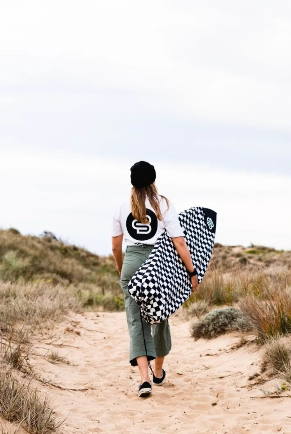 Boardsox shortboard cover being carried on a beach track