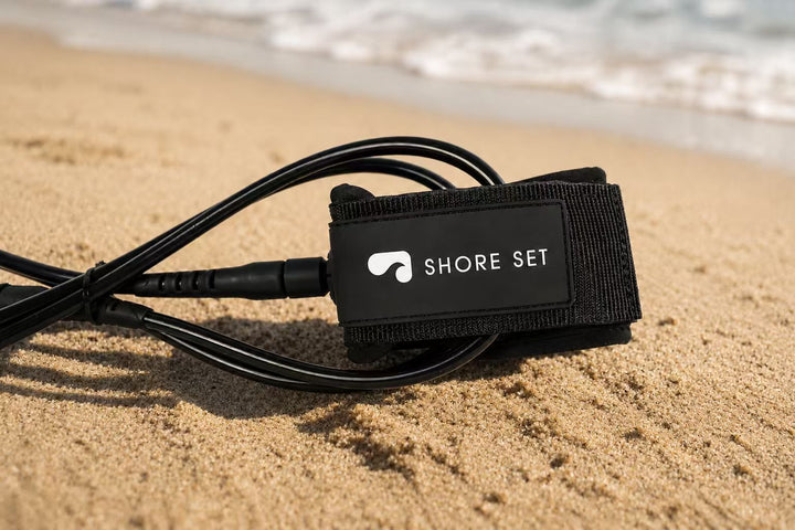 Shoreset surf leash coiled on the sand at the beach