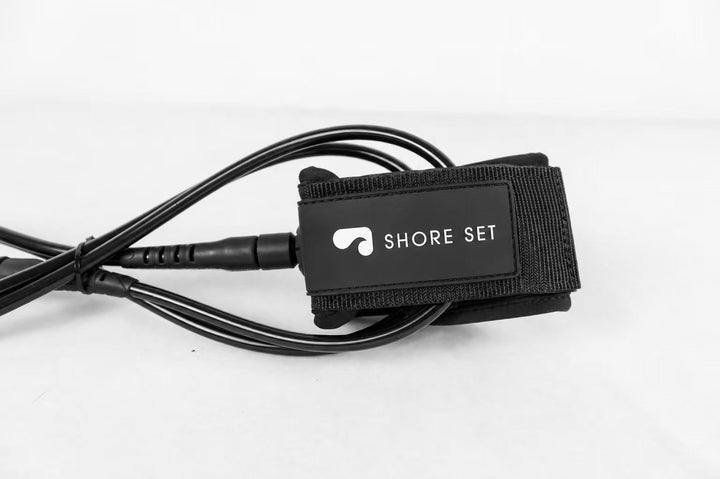 Shoreset black surf leash with white wave logo cuff, studio shot